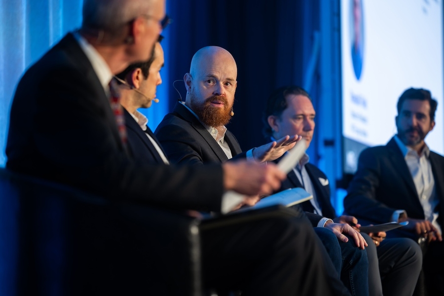 Five people sit on stage during a panel, focused on Sean James in the center.