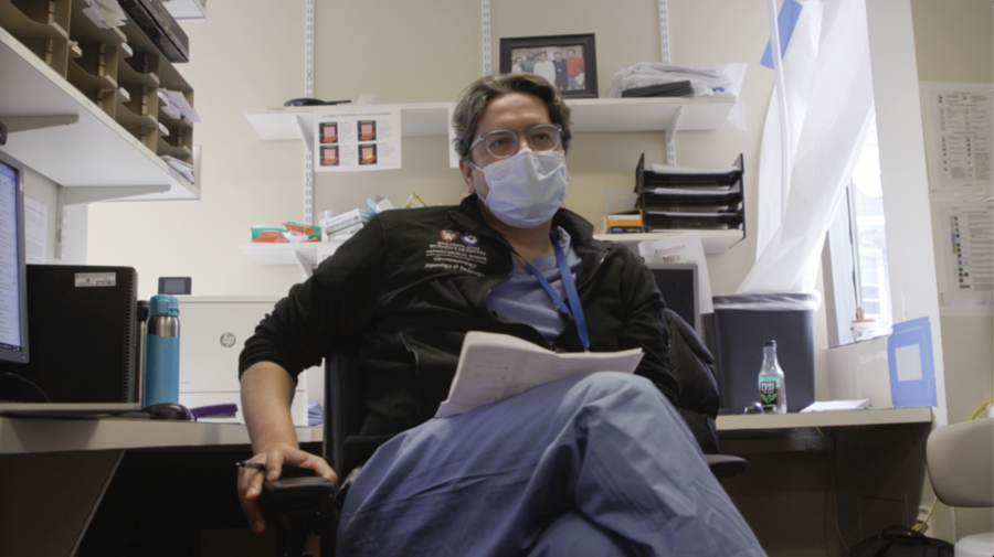 Giovanni Traverso wears hospital scrubs and protective gear, seated in an office. 