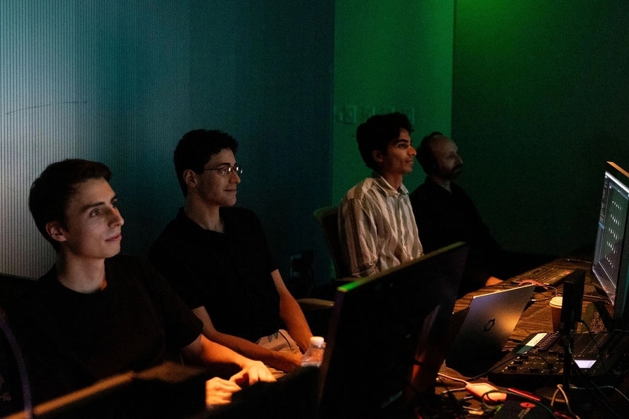Four men watch concert behind technology control system
