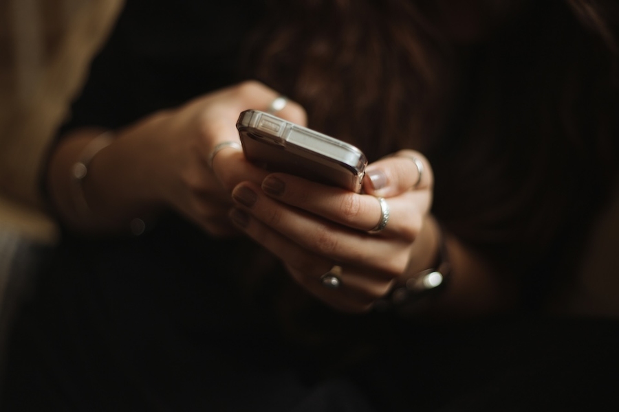 Close up of a pair of hands clasping a cell phone.