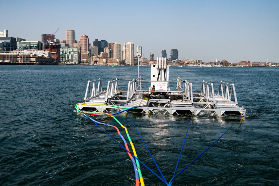 A metal frame floats in Boston Harbor, with the city in the distance.