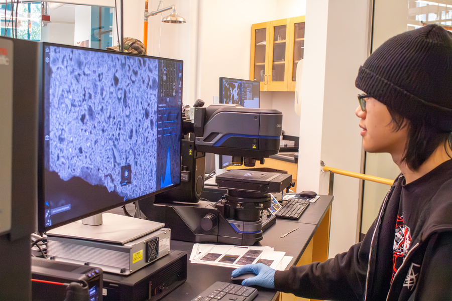An MIT student in a black cap looks at a monitor that shows the magnification of a material.