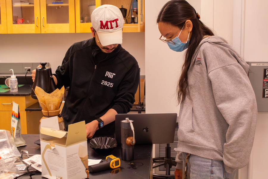 Omar Orozco and Elaine Jutamulia stand at a lab table, while Orozco prepares to pour hot water over coffee in a filter.