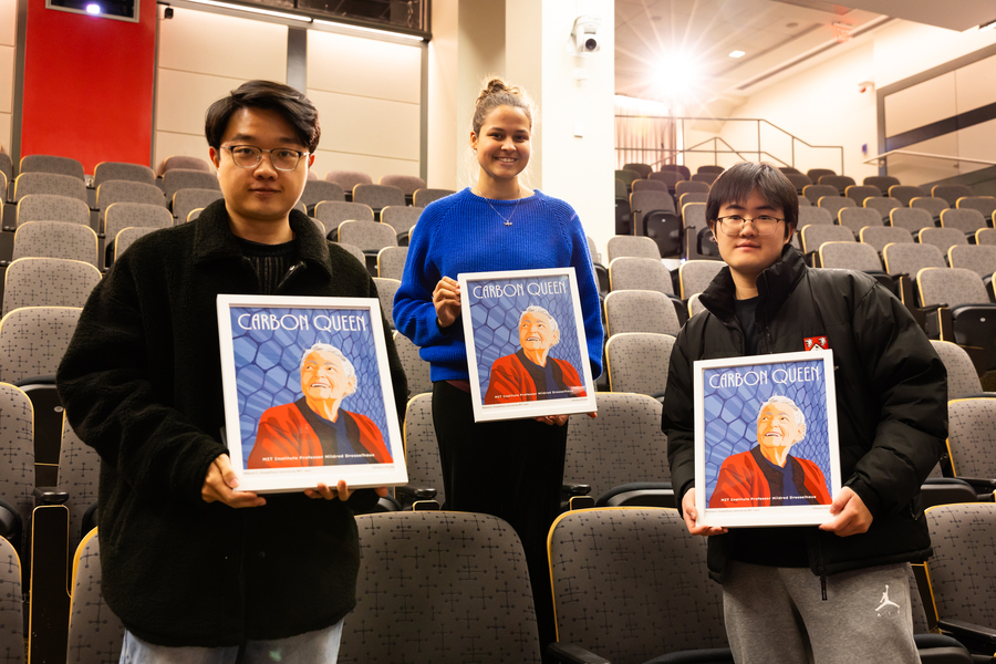 Three people hold framed posters featuring MIT Institute Professor Mildred S. Dresselhaus.