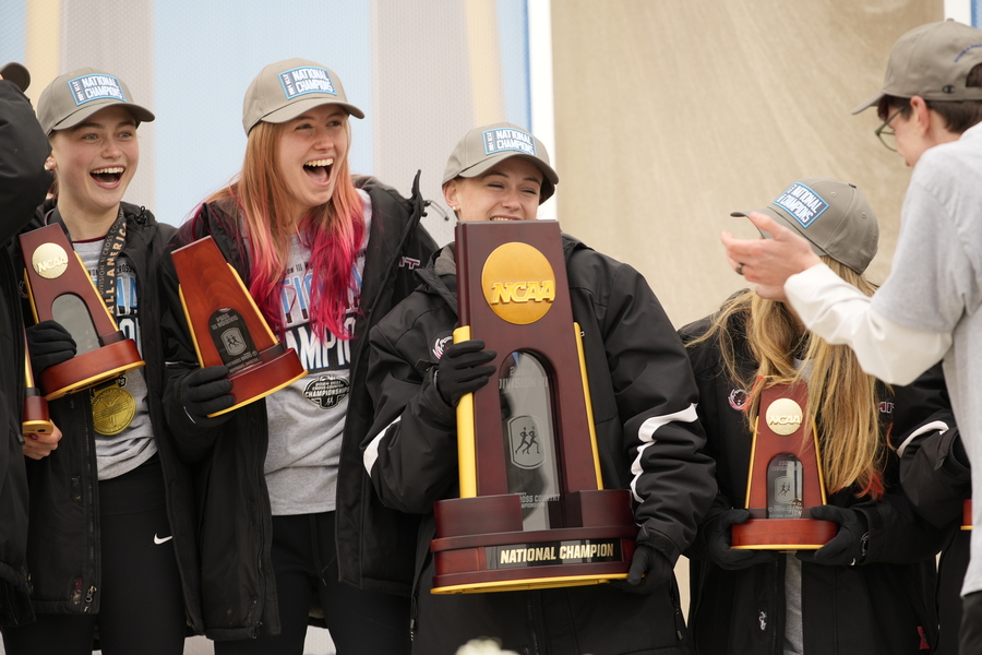 Several MIT athletes celebrate with the trophy