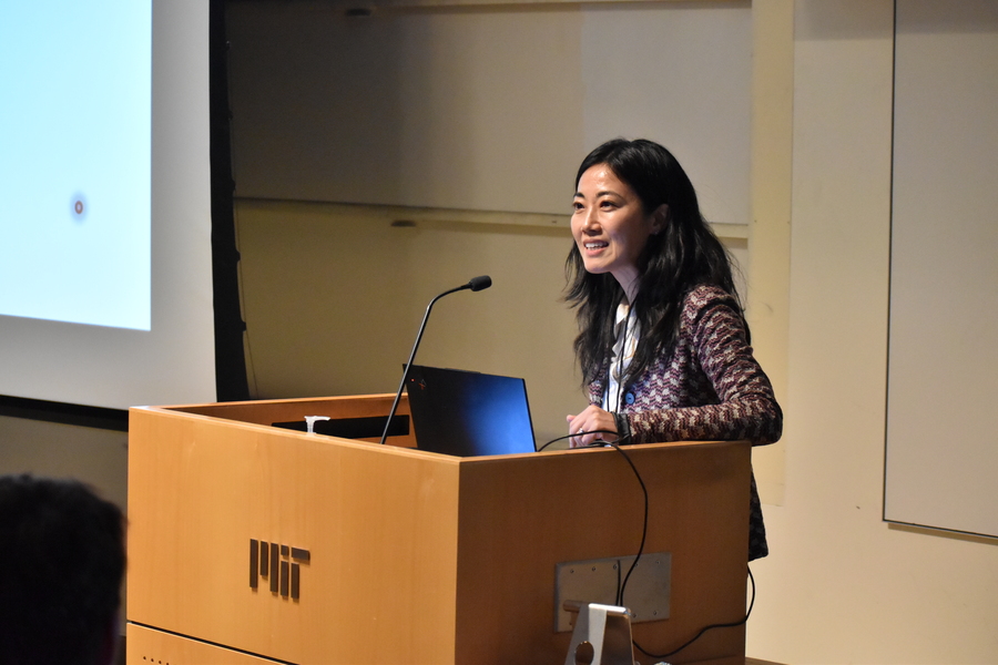 Gloria Choi speaks at a lectern with an open laptop screen facing her.