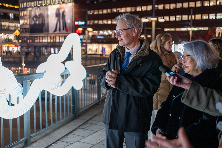 Victor Ambros and Candy Lee delight at seeing a rail decorated with lights at night in Stockholm