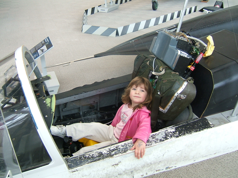 Faith Brooks as a child sits in the cockpit of a plane parked at a museum 