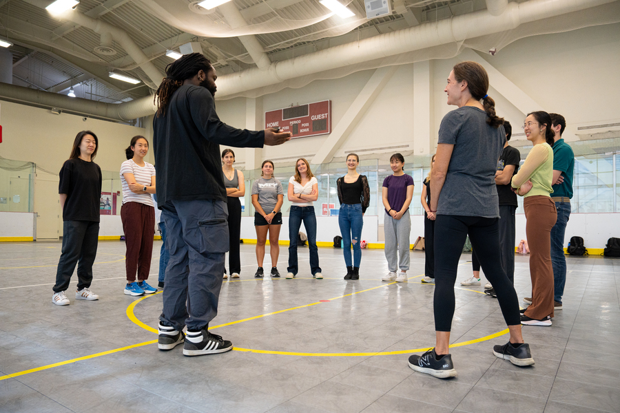 Instructor and students standing in a circle in a gymnasium