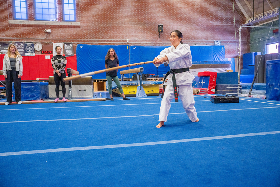 Woman wearing a white gi with a black belt demonstrates martial arts