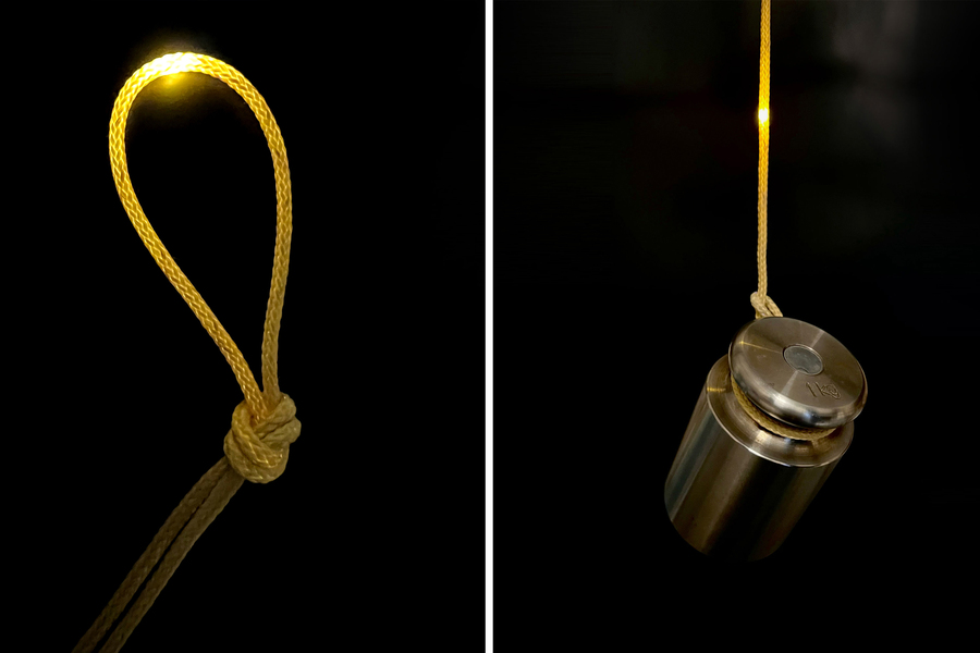 Operating fiber computer shown knotted, and hanging with a one kilogram weight attached.