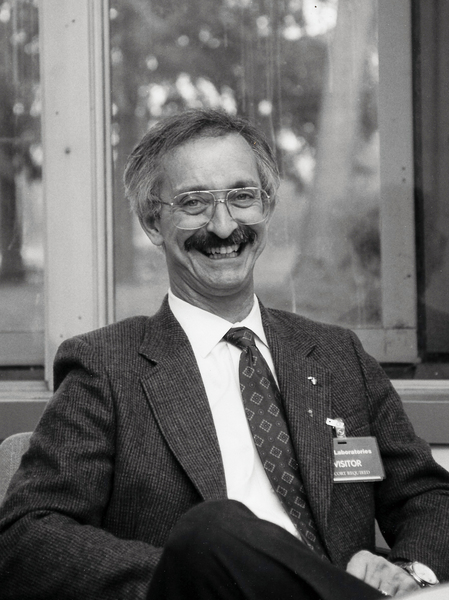 Grayscale photo of MIT professor Woodie Flowers seated and smiling at the camera