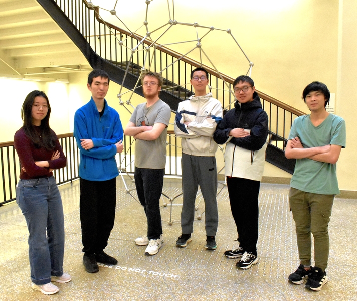 Six students pose with arms folded in front of the Dept. of Mathematics' Chord sculpture. 