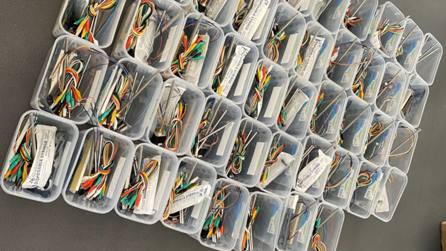 Rows of plastic boxes hold components necessary to build medical kits. About 30 are visible in this photo.