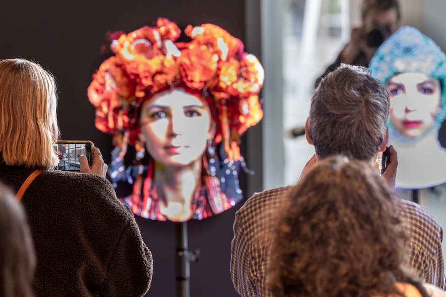 Spectators view images of women in colorful headwear