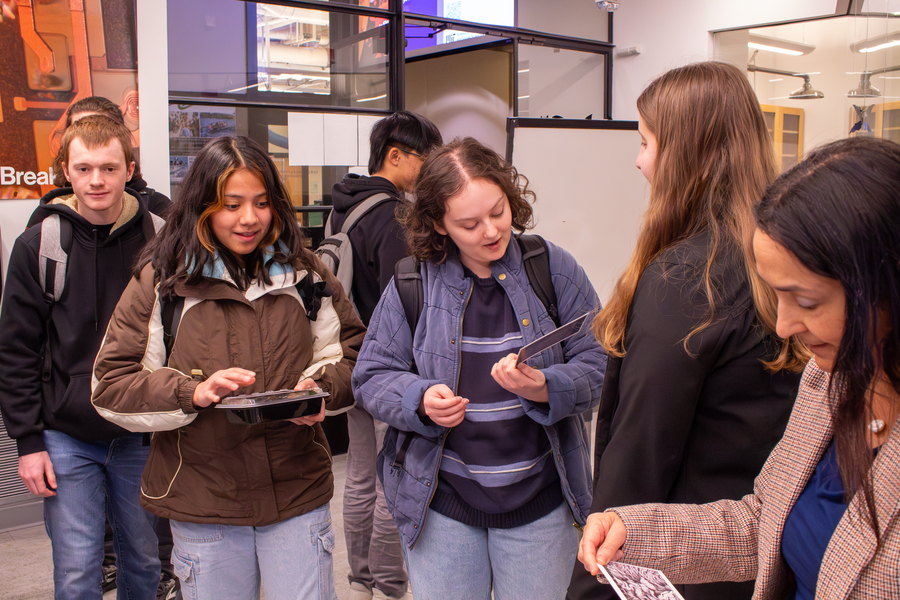 Half-a-dozen students in MIT's Breakerspace lounge and lab look at postcards of winning images