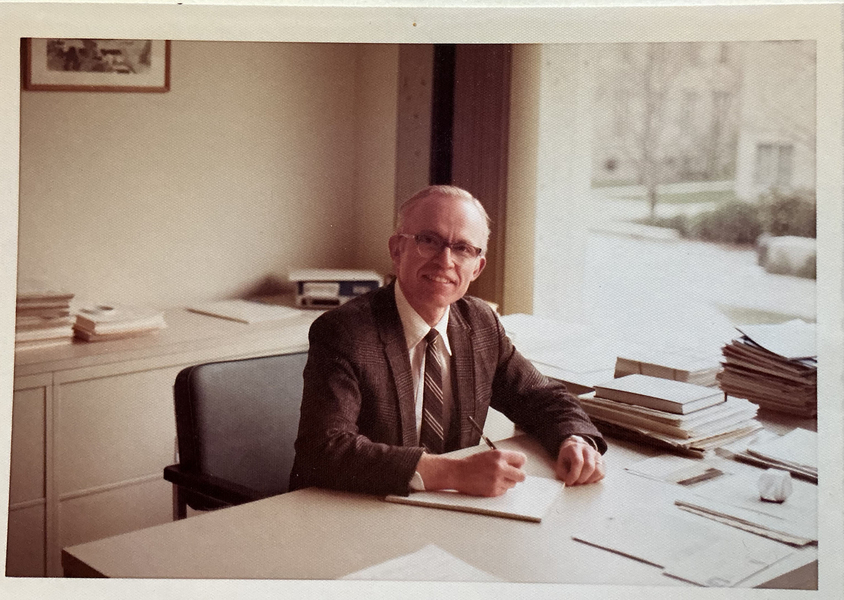 Grainy sepia-tinted photo of Fred Greene in middle age, seated at an office desk