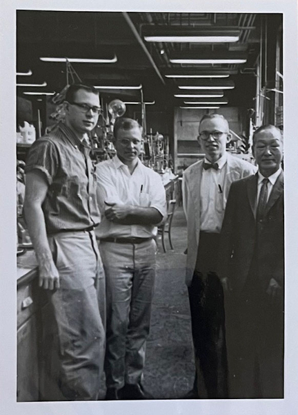 Grayscale photo of a young Fred Greene standing with three students