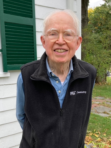 Fred Greene stands in front of a white house, wearing an MIT Chemistry fleece
