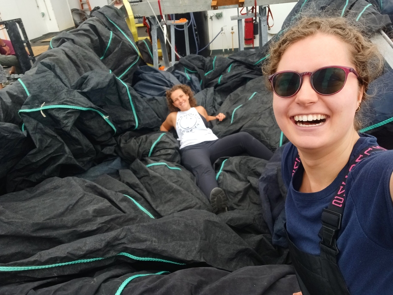 Two people on a large boat with huge black nets.