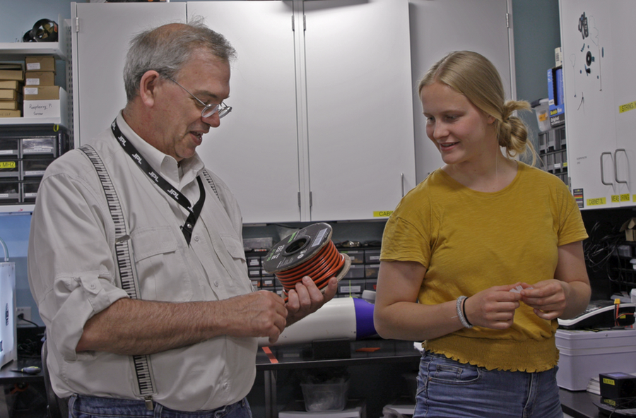 Andrew Bennett and Teagan Sullivan look at a spool of wiring for an underwater robot. 