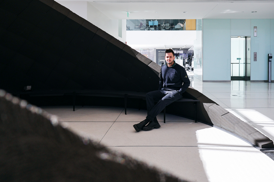 A man sits on the edge of a large, curved architectural structure.