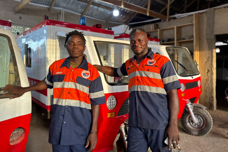 Two members of the Moving Health team standing by motorized ambulances