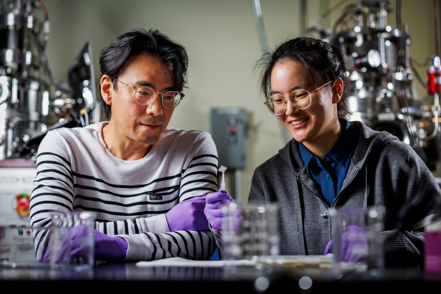 Jeehwan Kim, left, and Xinyuan Zhang look at printed square material in lab.