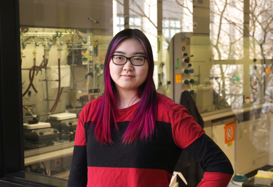 Madison Wang, wearing a red-and-black striped top, in a laboratory