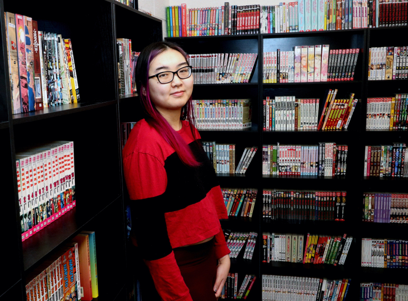 Madison Wang stands near bookshelves filled with manga-style books