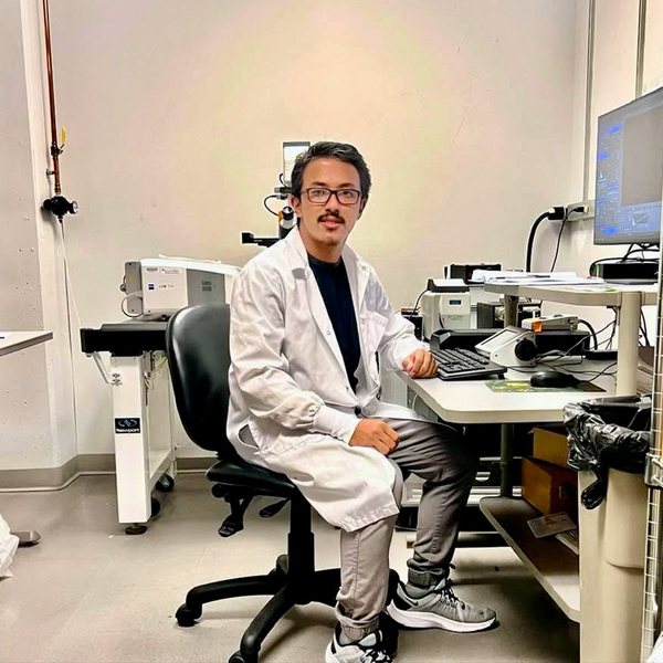 Mingmar Sherpa wears a lab coat and sits at a computer