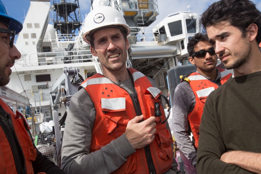 Four ocean researchers stand together on the deck of a large ship.