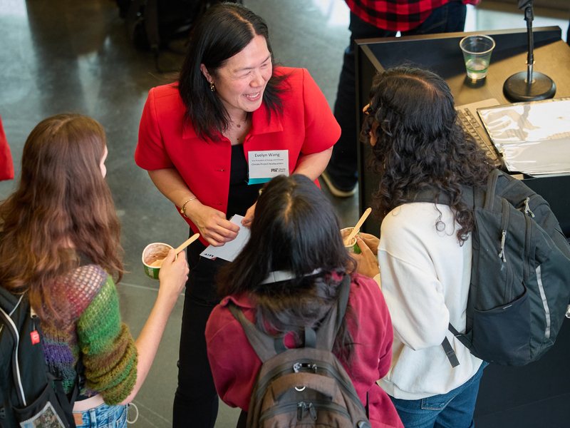 Seen from above, Evelyn Wang laughs as she talks with three students gathered around her.