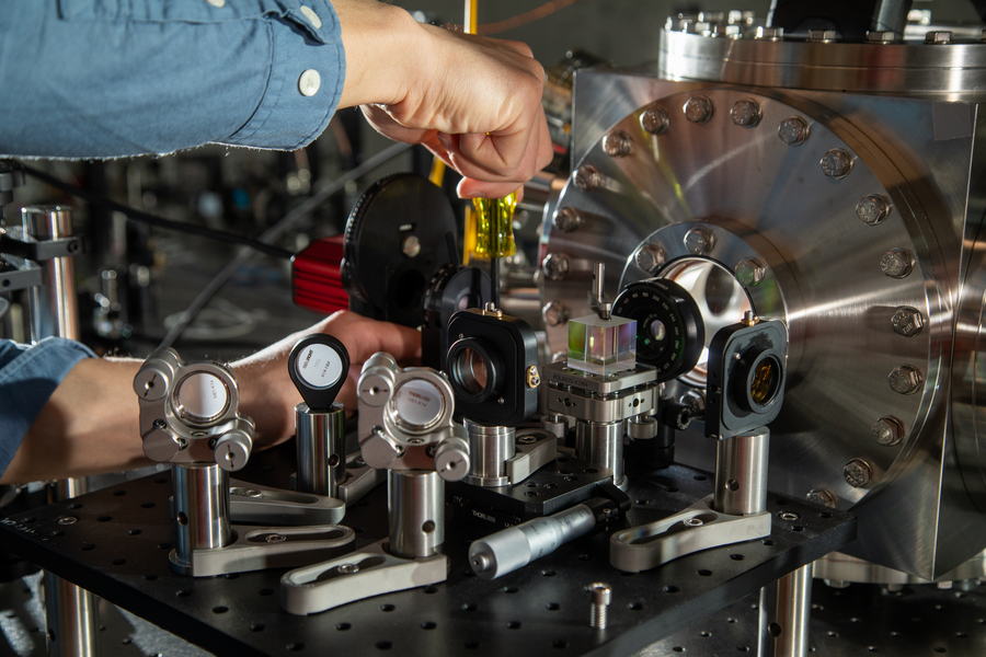 Closeup of a hand reaching in to adjust an experimental optical set up.