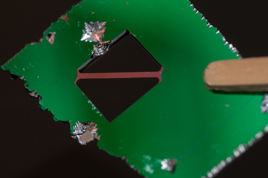 A rectangular green piece with a smaller square mirrored object on top
