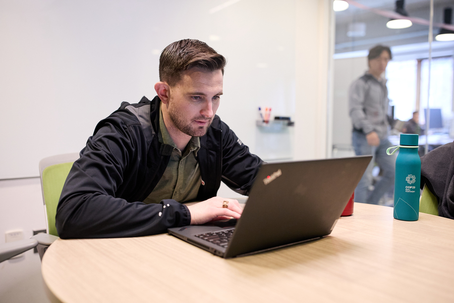 David Brown sits at a laptop on a round conference table.