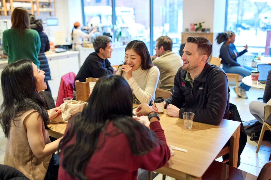 David Brown laughs with three other people seated in a busy coffee shop
