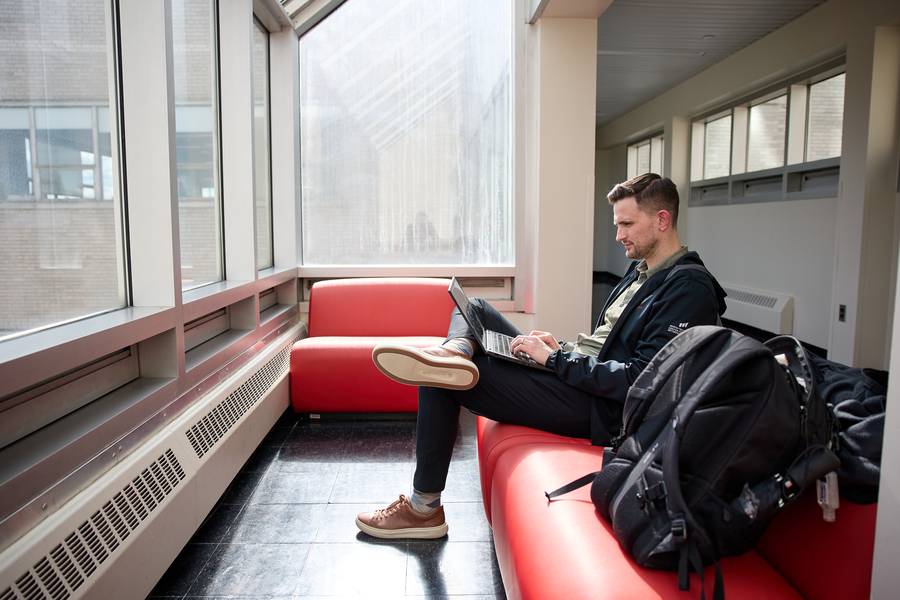 David Brown works at his laptop while sitting on the couch on the sky bridge between the Tang Center and the Morris and Sophie Chang Building.