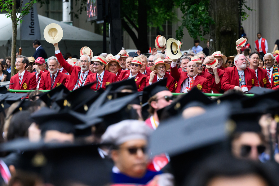 Members of MIT’s Class of 1975, seated and waving hats in the air