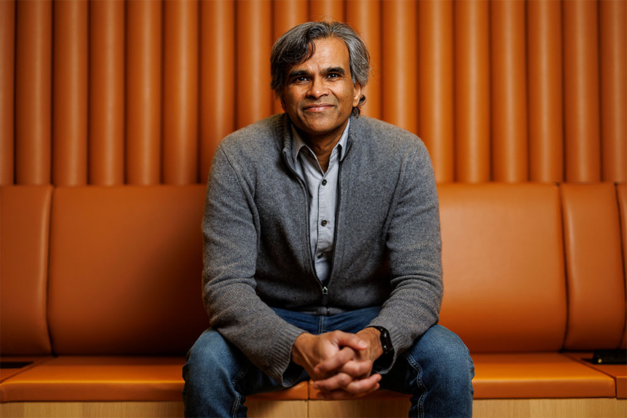 Sendhil Mullainathan poses for a photo on an orange lounge chair 