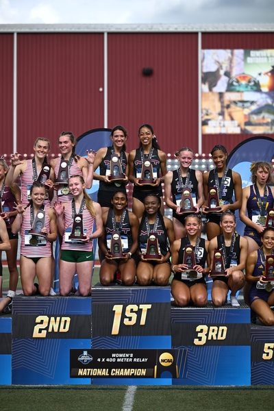 Four MIT runners on the 1st place podium receiving their trophies. There are 8 more runners from two other schools on the 2nd and 3rd place platforms