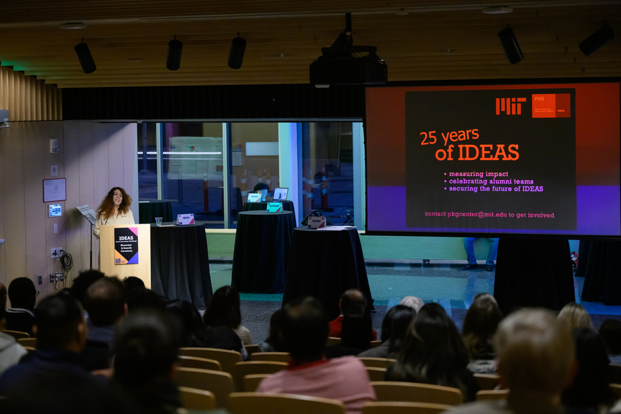 Christine Ortiz at a podium next to a presentation slide in a darkened auditorium.