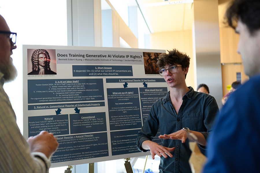 A young man discusses his research poster titled "Does Training Generative AI Violate IP Rights?" at an academic symposium.