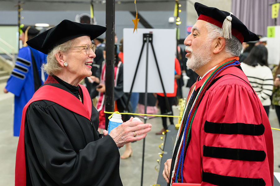 Mary Robinson and Hashim Sarkis, both in colorful academic regalia, speak to each other in a backstage setting.