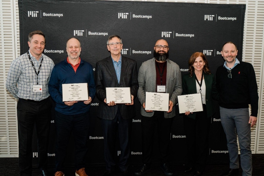 Six people pose side by side. Four are holding their program certificates.
