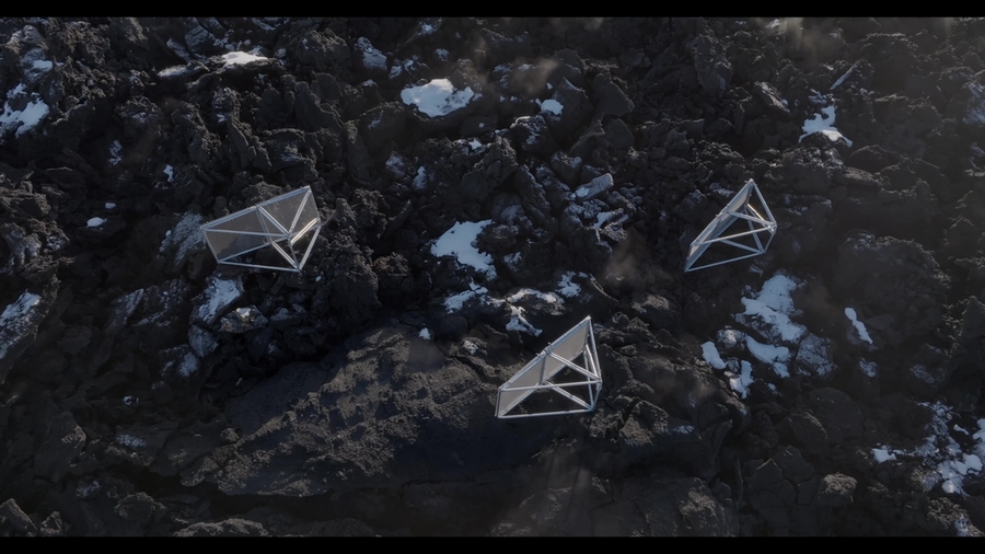 Aerial photo of three triangular metal framework objects in a lava field.
