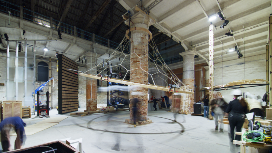 A large brick column with a geometric, weblike net structure suspended from the ceiling.
