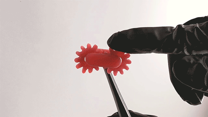 A gloved finger spins a resin with two gears that move away from each other.
