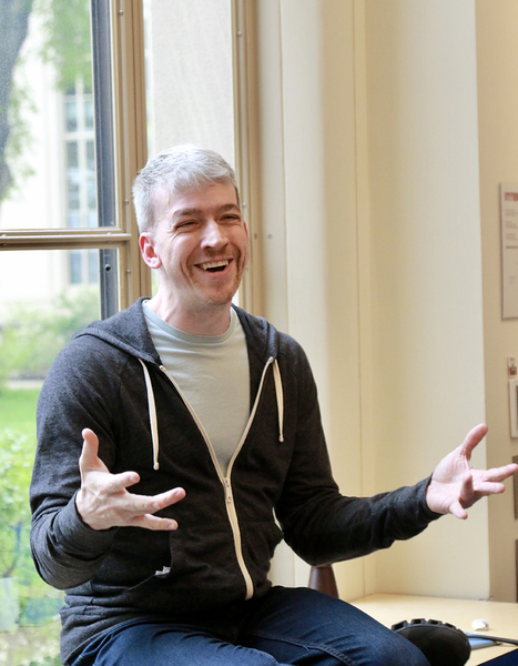 Arthur Bahr sits on a window sill, gesturing as he talks