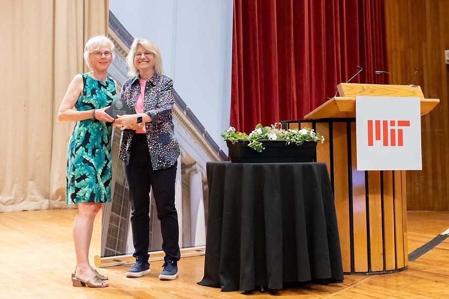 Kathleen Monagle and MIT President Sally Kornbluth pose together on a stage. They both hold a Collier Medal.